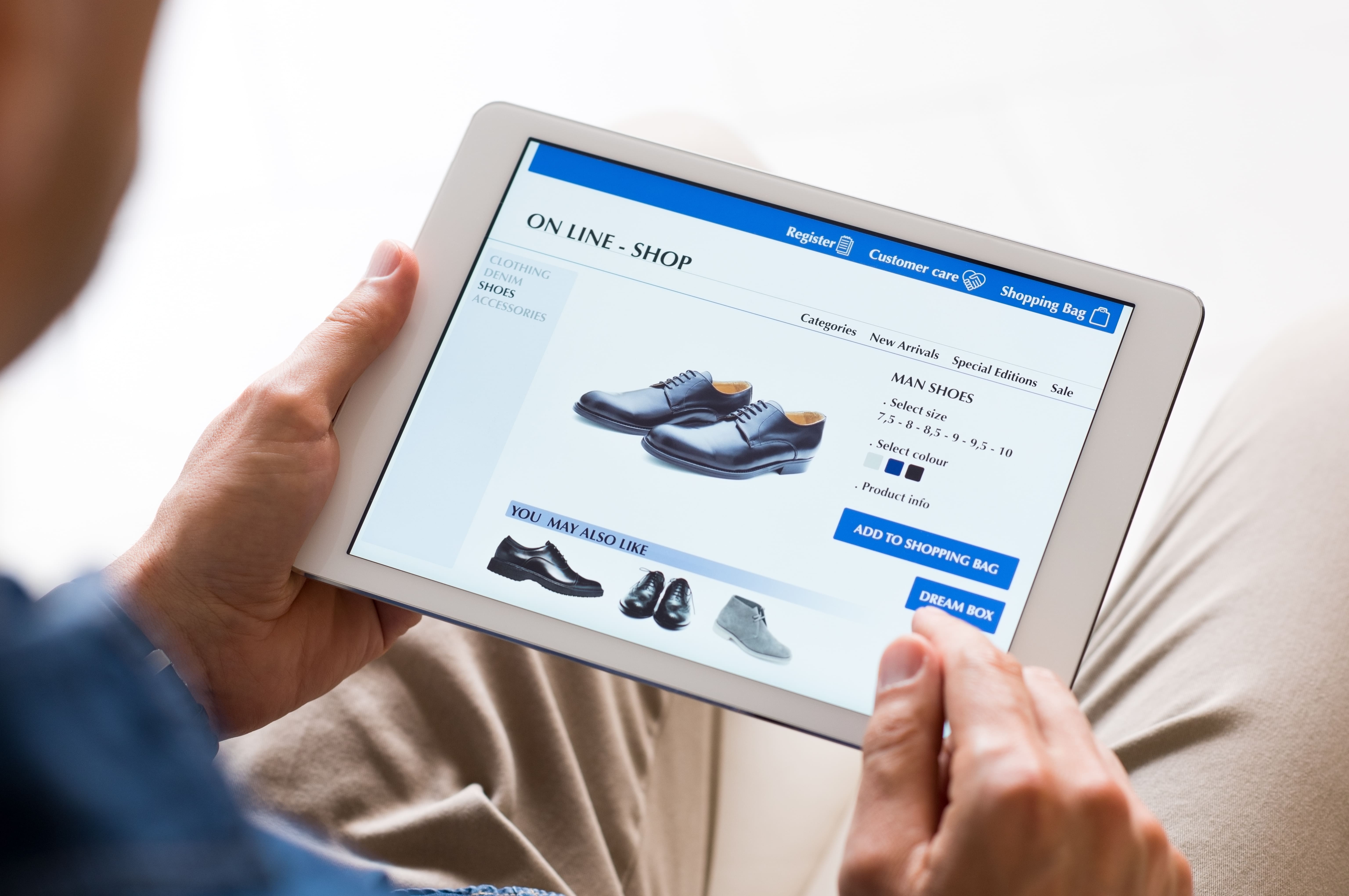 Young man looking at shoes online. Man looking at various shoes options over internet through digital tablet. Casual man makes online shopping at home with digital tablet.